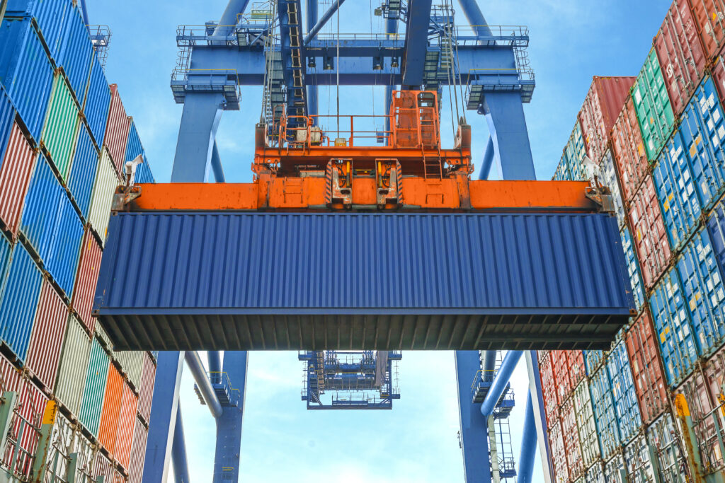 Importer shipping container. Shore crane loading containers at east coast port or west coast port