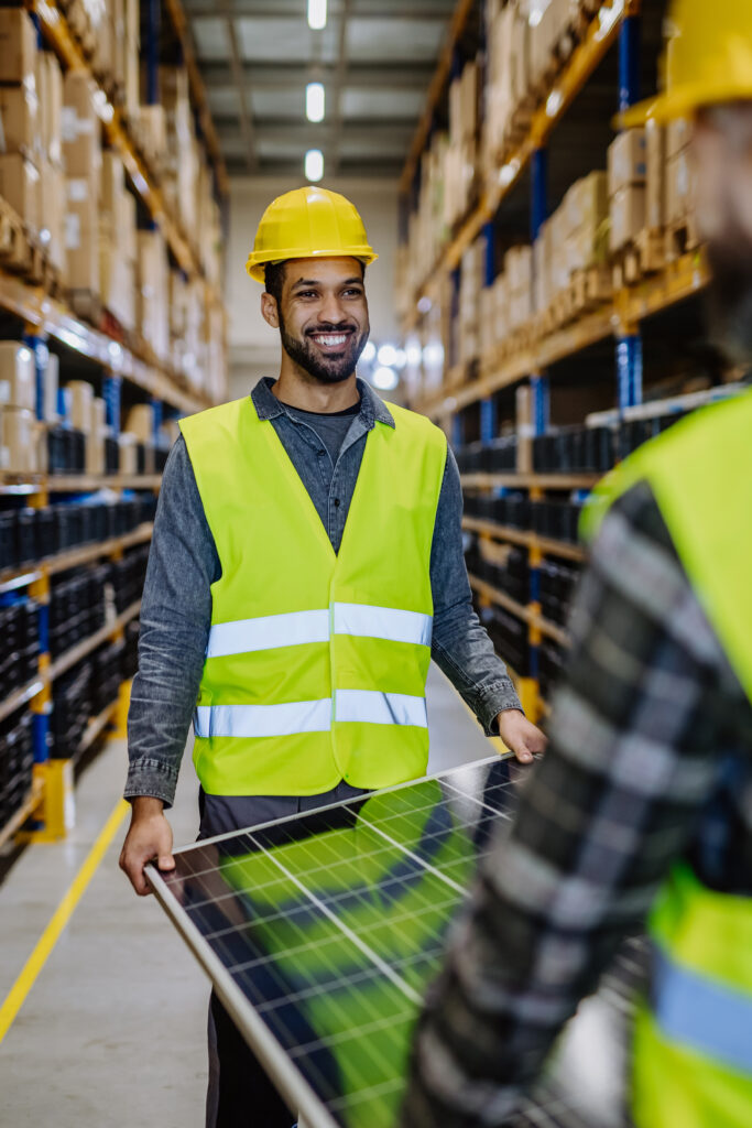 Storage for solar products. Warehouse worker safely carries a solar panel.